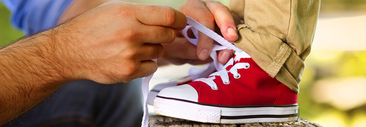 Caregiver tying child's shoe lace