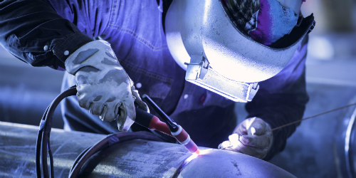 Worker TIG welding a pipe