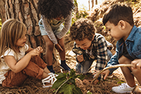 Four kids examining nature with a magnifying glass