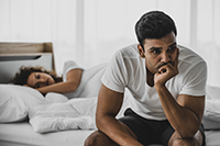 Worried husband sitting next to wife in bed