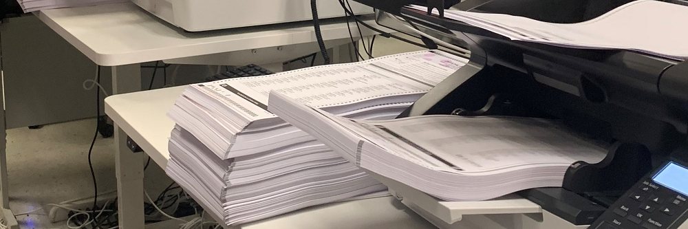 A stack of ballots being run through a scanner.