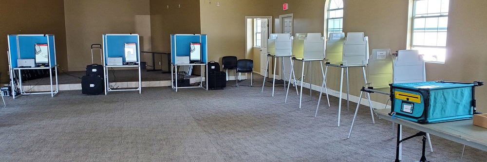 A picture of a Vote Center with three ICX accessible voting booths along the top wall and four standard voting booths along the right wall.
