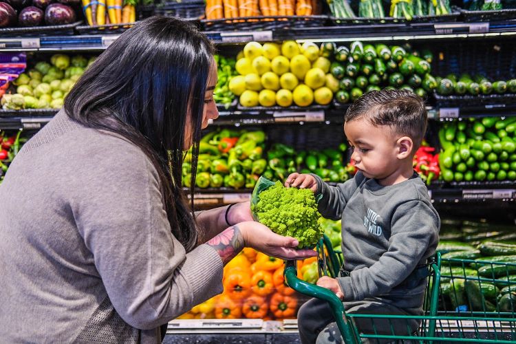 Woman and child at grocery store picking out produce